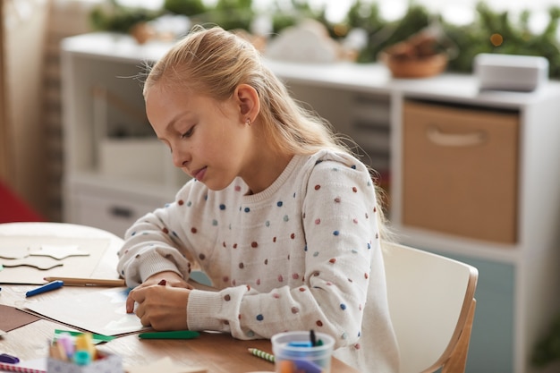 Retrato de uma adolescente loira desenhando em casa ou aproveitando as aulas de arte e artesanato na escola