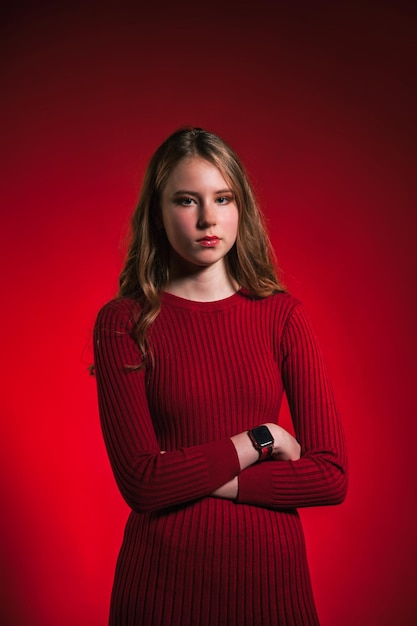 Retrato de uma adolescente muito triste em um vestido vermelho estiloso sobre fundo vermelho olhando para a câmera