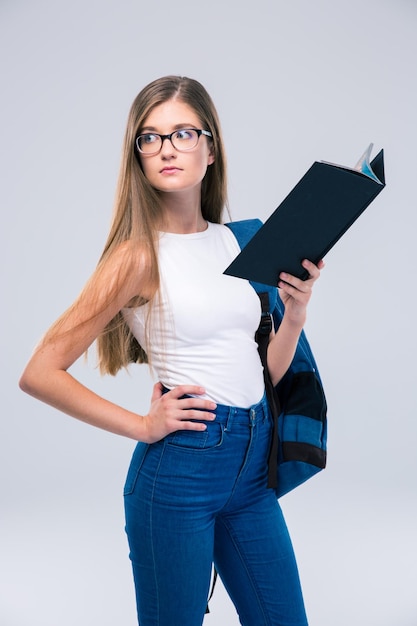 Retrato de uma adolescente pensativa segurando um livro e desviando o olhar isolado