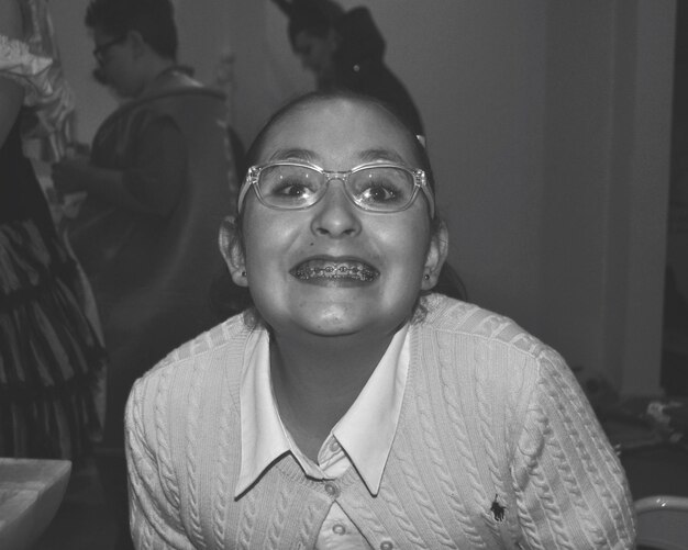 Foto retrato de uma adolescente sorridente usando aparelhos ortopédicos e óculos em casa