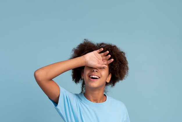 Foto retrato de uma adolescente sorrindo e cobrindo os olhos