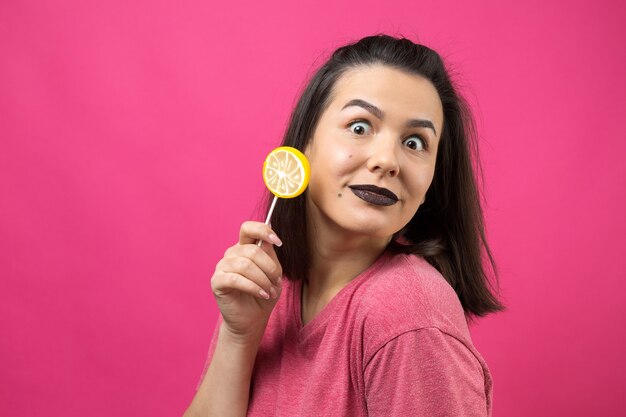 Retrato de uma adorável doce linda mulher alegre com cabelo castanho liso segurando um pirulito