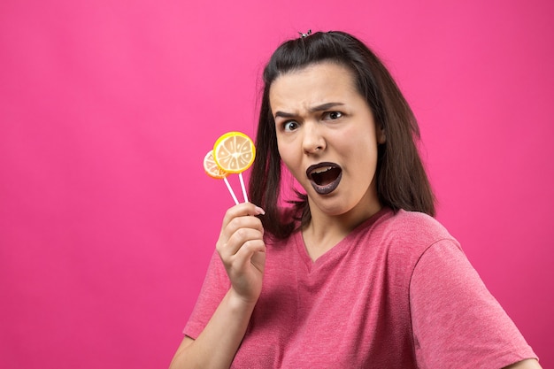 Retrato de uma adorável doce linda mulher alegre com cabelo castanho liso segurando um pirulito