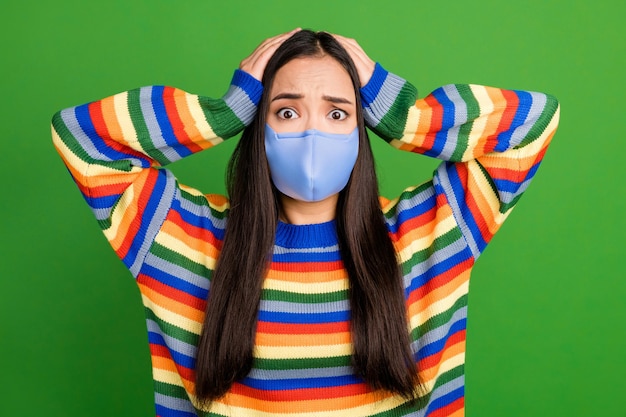 Retrato de uma adorável garota preocupada assistir tv ouvir más notícias vítimas cobiçosas usam máscara isolada sobre fundo de cor verde vibrante