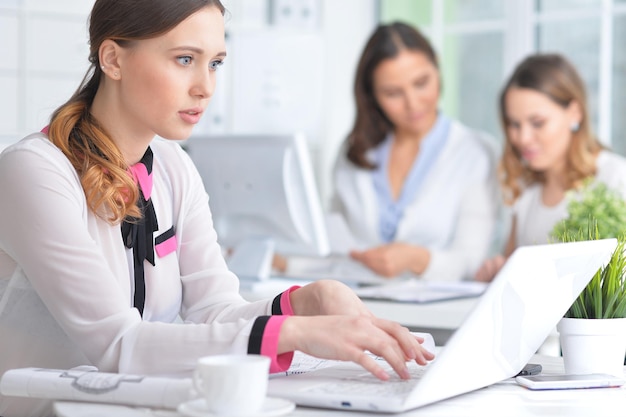 Retrato de uma agradável mulher de negócios com um laptop no escritório