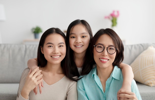 Retrato de uma alegre família asiática de mãe madura, filha adulta e netinha sorrindo para