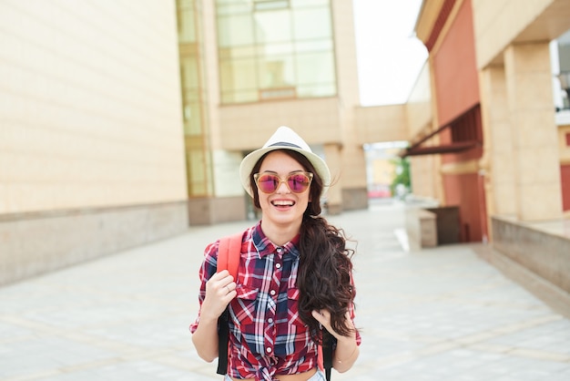 Retrato de uma alegre garota turistas no fundo do edifício com uma fachada de vidro