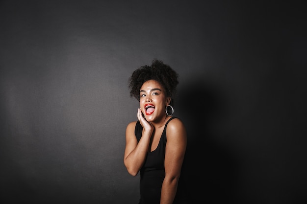 Retrato de uma alegre mulher afro-americana com um vestido preto de pé