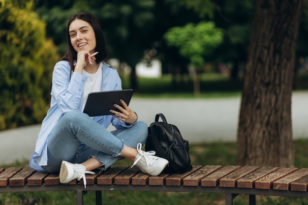 Retrato de uma aluna atraente vestindo uma camisa azul usa um tablet para estudar Copiar espaço