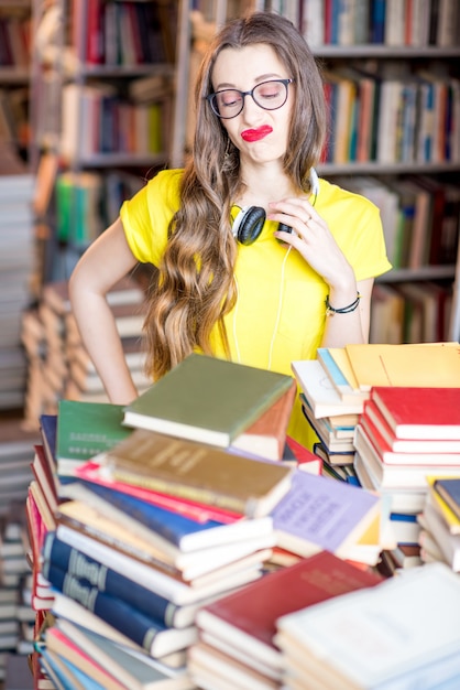 Retrato de uma aluna cansada estudando com livros na biblioteca