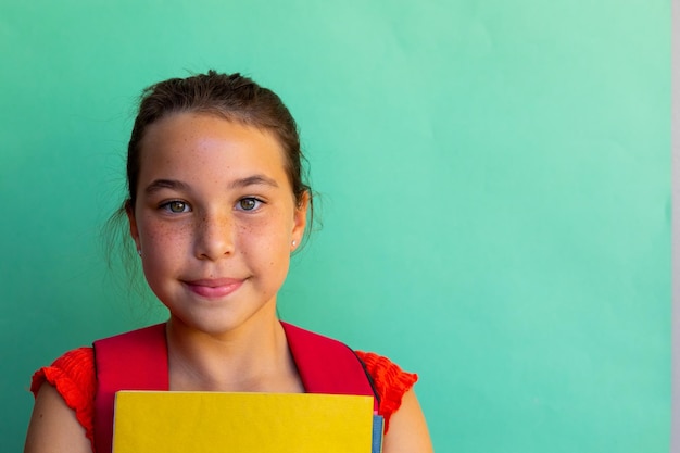 Foto retrato de uma aluna caucasiana feliz com livros sobre fundo azul