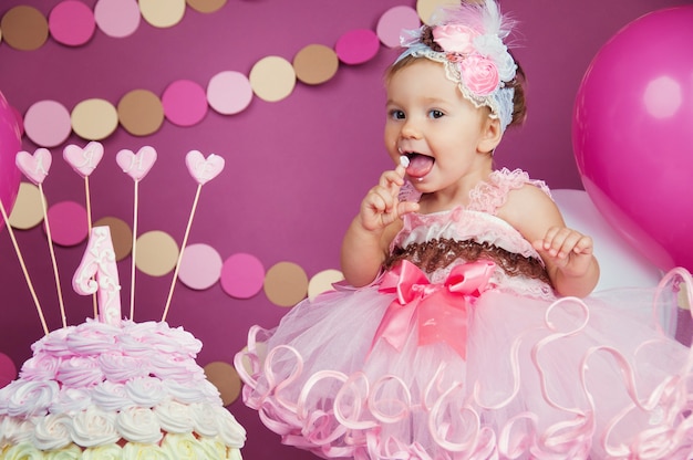 Retrato de uma aniversariante alegre com o primeiro bolo. Comendo o primeiro bolo. Quebre o bolo.