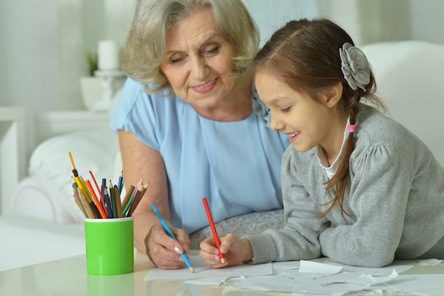 Retrato de uma avó feliz com a neta a desenhar juntos