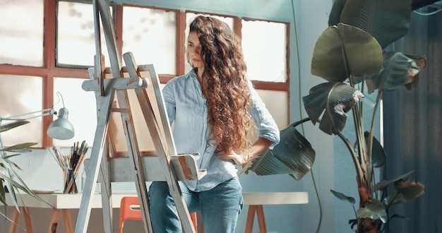 Retrato de uma bela artista feminina de cabelos compridos no trabalho em sua tela em um estúdio