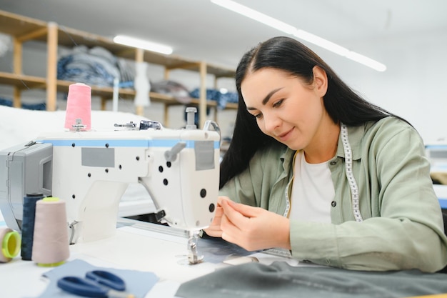 Retrato de uma bela costureira carregando uma fita métrica e trabalhando em uma fábrica têxtil
