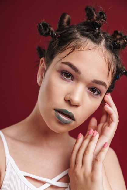 Retrato de uma bela e incrível jovem adolescente punk posando isolada sobre uma parede vermelha cor de vinho