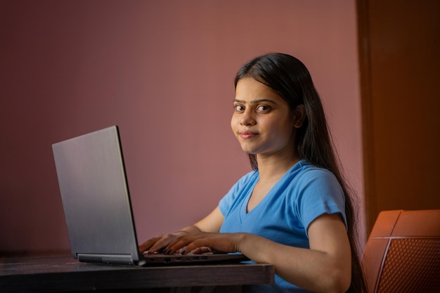 Retrato de uma bela e jovem mulher indiana trabalhando em seu laptop