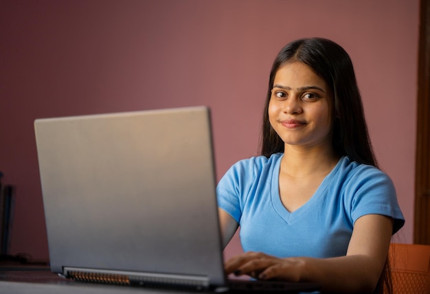 Retrato de uma bela e jovem mulher indiana trabalhando em seu laptop