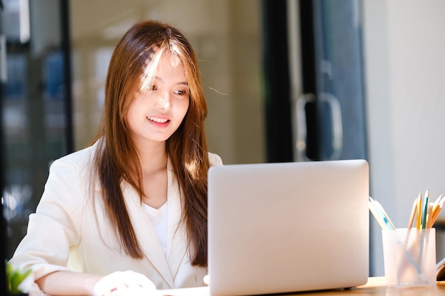 Retrato de uma bela e sorridente jovem empresária empreendedora trabalhando na estação de trabalho moderna