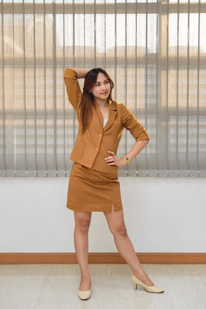 Retrato de uma bela empresária asiática usa vestido amarelo em um escritórioAs pessoas da Tailândia usam uniformes femininos