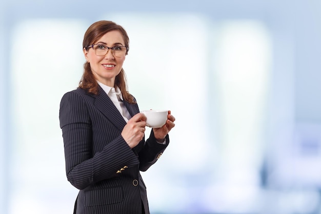 Retrato de uma bela empresária de 50 orelhas com uma xícara de café no escritório