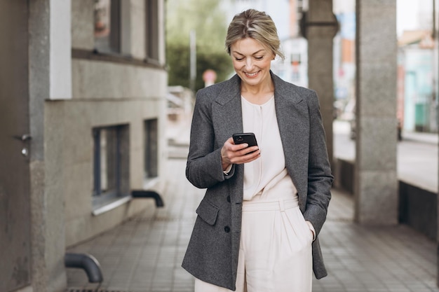 Retrato de uma bela empresária madura sorrindo e falando ao telefone no meio urbano moderno
