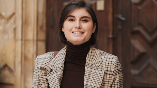 Retrato de uma bela empresária sorridente usando suéter de gola alta parecendo feliz na câmera ao ar livre