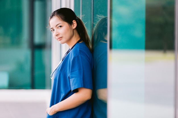 Retrato de uma bela enfermeira asiática de uniforme do lado de fora do hospital