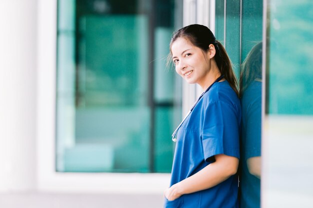 Retrato de uma bela enfermeira asiática de uniforme do lado de fora do hospital