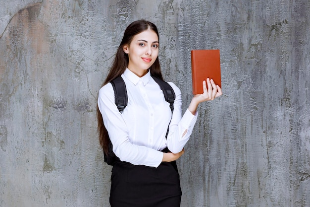 Retrato de uma bela estudante com livro em pé sobre cinza. Foto de alta qualidade