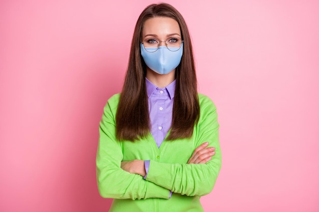 Retrato de uma bela garota atraente nerd geek de braços cruzados usando máscara médica isolada sobre fundo de cor rosa pastel