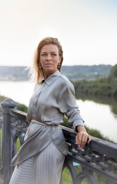 Foto retrato de uma bela garota loira em um vestido cinza na ponte