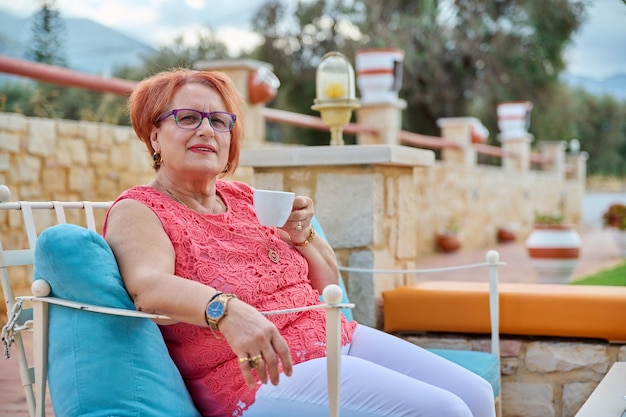 Retrato de uma bela idosa dos anos 70 relaxando com uma xícara