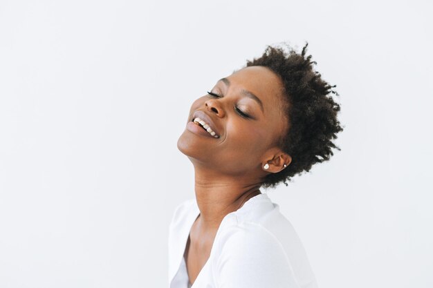 Foto retrato de uma bela jovem afro-americana feliz com olhos fechados em camiseta branca isolada