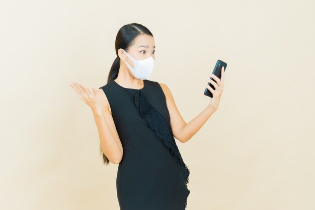 Retrato de uma bela jovem asiática com máscara para proteger covid19 ou vírus na parede de cor amarela