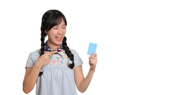 Retrato de uma bela jovem asiática feliz em vestido jeans segurando cartão de crédito em fundo branco