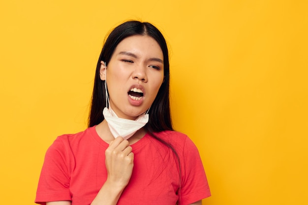 Retrato de uma bela jovem asiática posando máscara médica fechada com fundo isolado inalterado