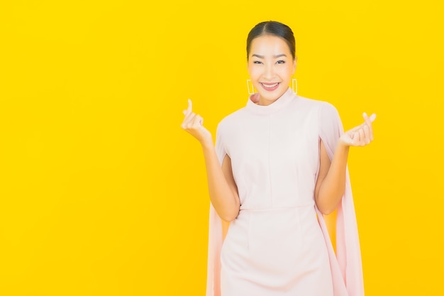 Retrato de uma bela jovem asiática sorrindo com muita ação na parede amarela