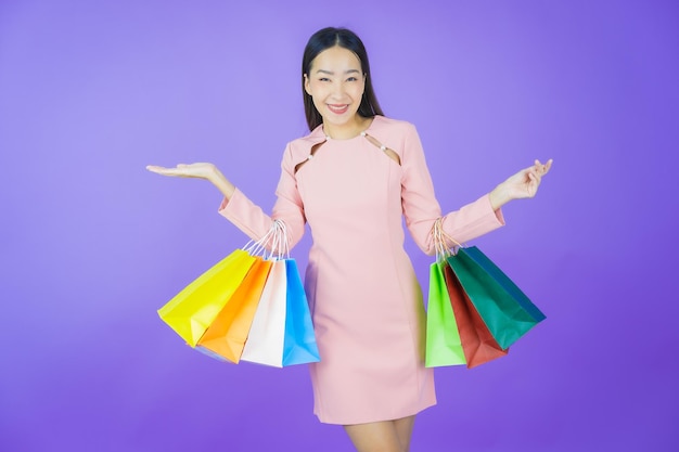 Retrato de uma bela jovem asiática sorrindo com uma sacola de compras na cor de fundo