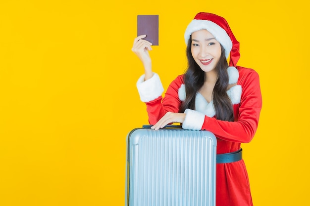 Retrato de uma bela jovem asiática usando fantasia de Natal com bolsa de bagagem em amarelo.
