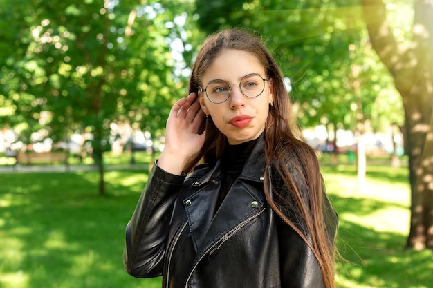 Retrato de uma bela jovem atraente em óculos no belo verão verde ou parque primavera