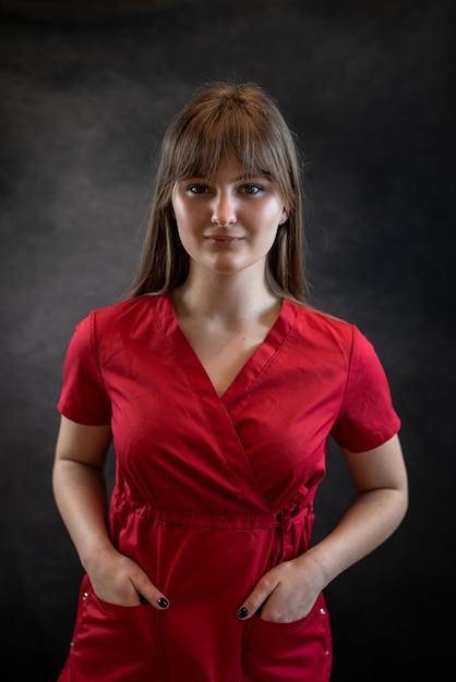 Retrato de uma bela jovem caucasiana médica ou estagiária usa uniforme vermelho isolado