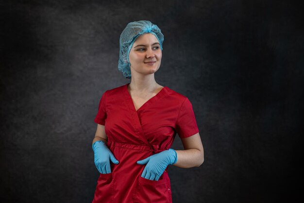 Retrato de uma bela jovem caucasiana médica ou estagiária usa uniforme vermelho isolado