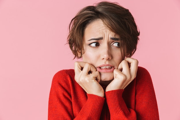 Foto retrato de uma bela jovem chocada e confusa, vestindo roupas vermelhas, isolado sobre um fundo rosa