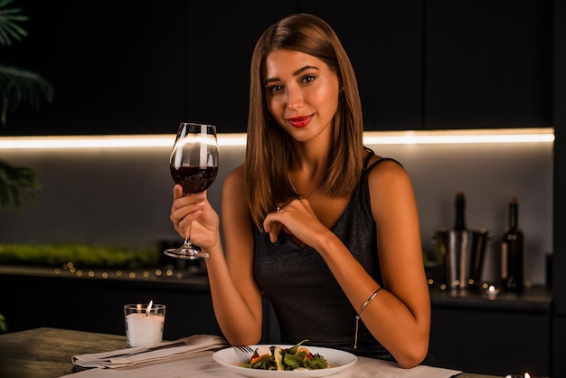 Retrato de uma bela jovem com copo de vinho tinto de luxo dentro de casa