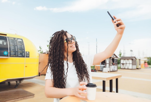 Retrato de uma bela jovem com fones de ouvido que ouve música enquanto está sentado em um café de ruaAproveite a geração de música Z