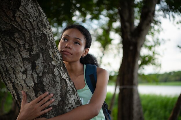 Foto retrato de uma bela jovem com mochila de pé e banho na floresta