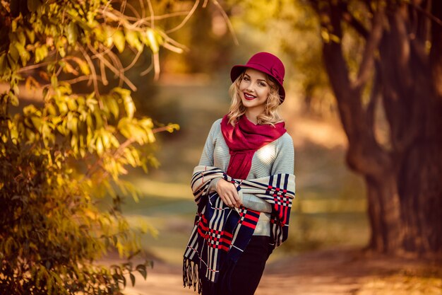 Retrato de uma bela jovem com um chapéu cor de vinho no outono em um passeio no parque