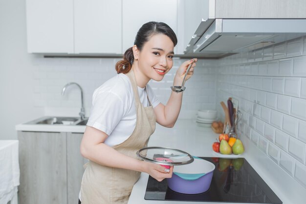 Retrato de uma bela jovem cozinhando sopa com legumes em casa