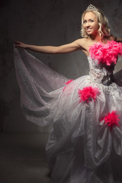 Retrato de uma bela jovem de vestido de noiva rosa e branco posando contra a parede